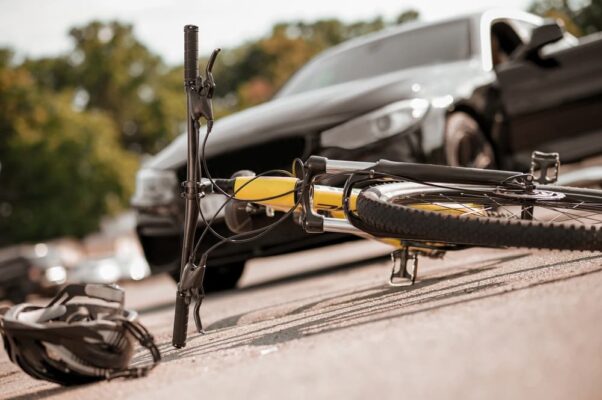 Bicycle and helmet lying on road and car
